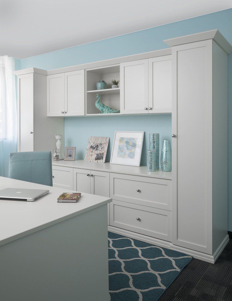 a desk and cabinet system with a laptop on it in a room with blue walls .