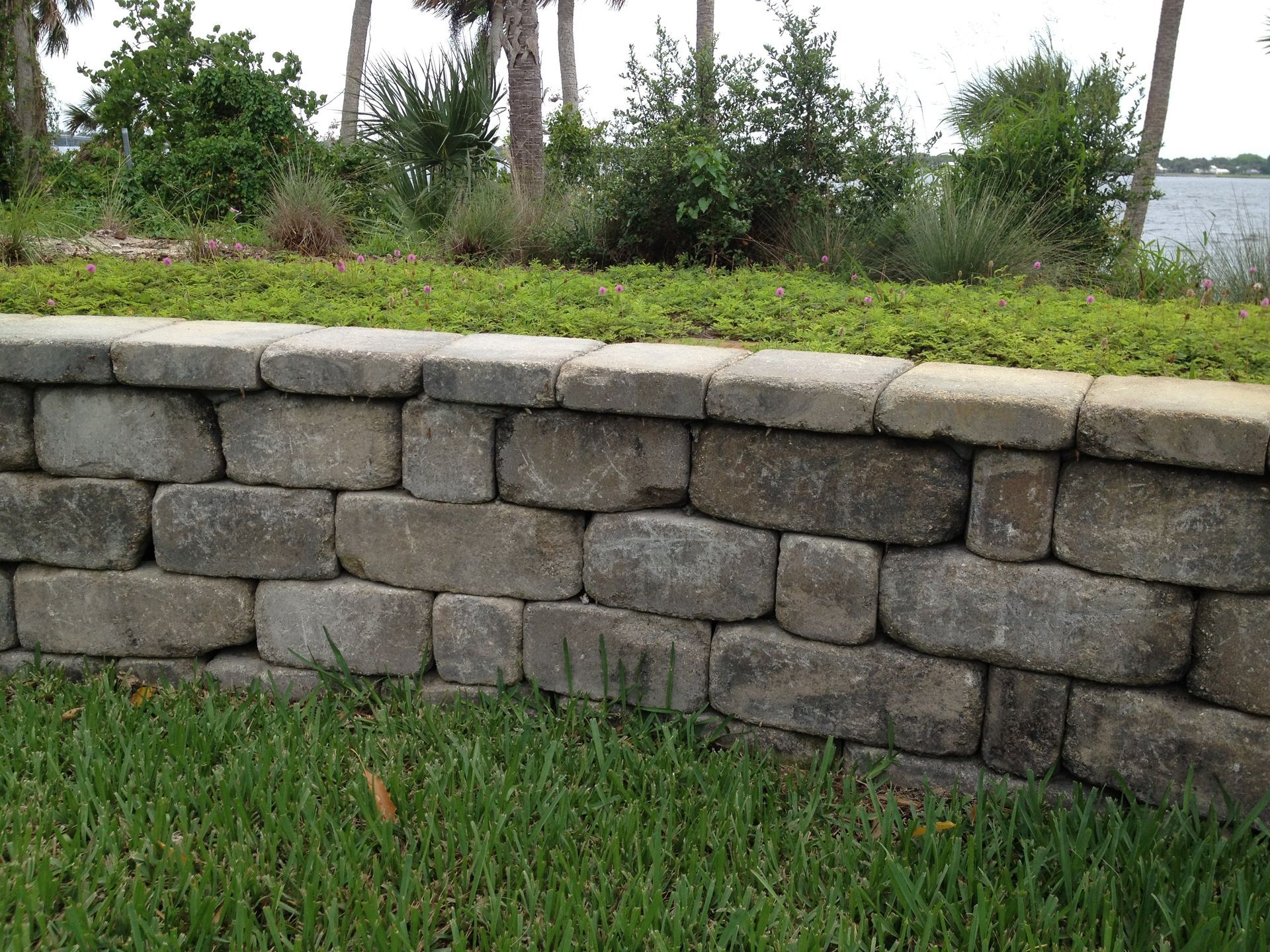 A stone wall is in the middle of a lush green field.