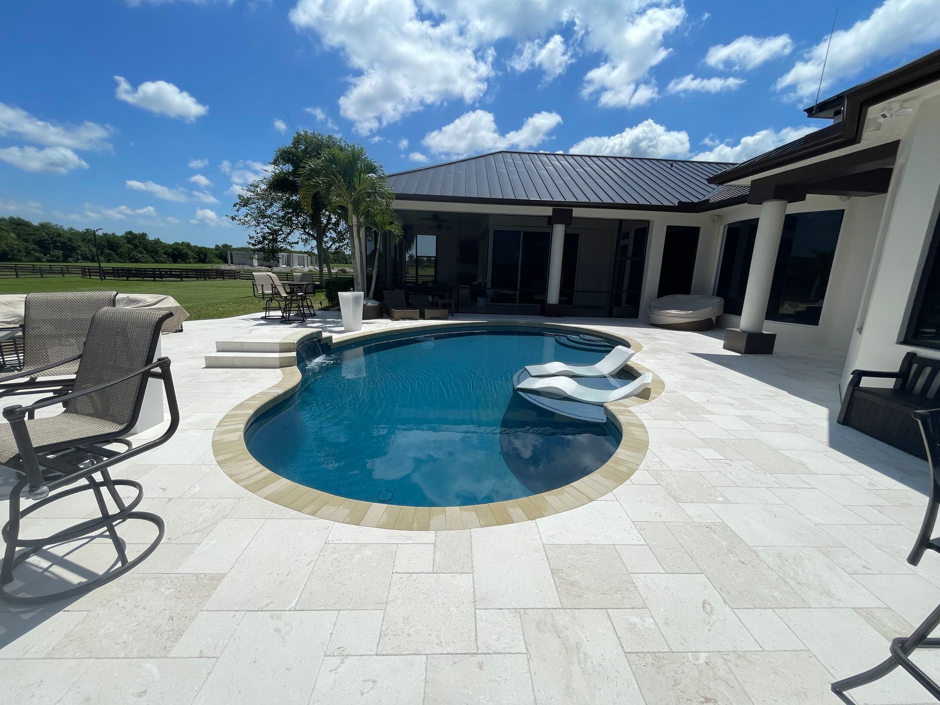 A large swimming pool is in the backyard of a house.