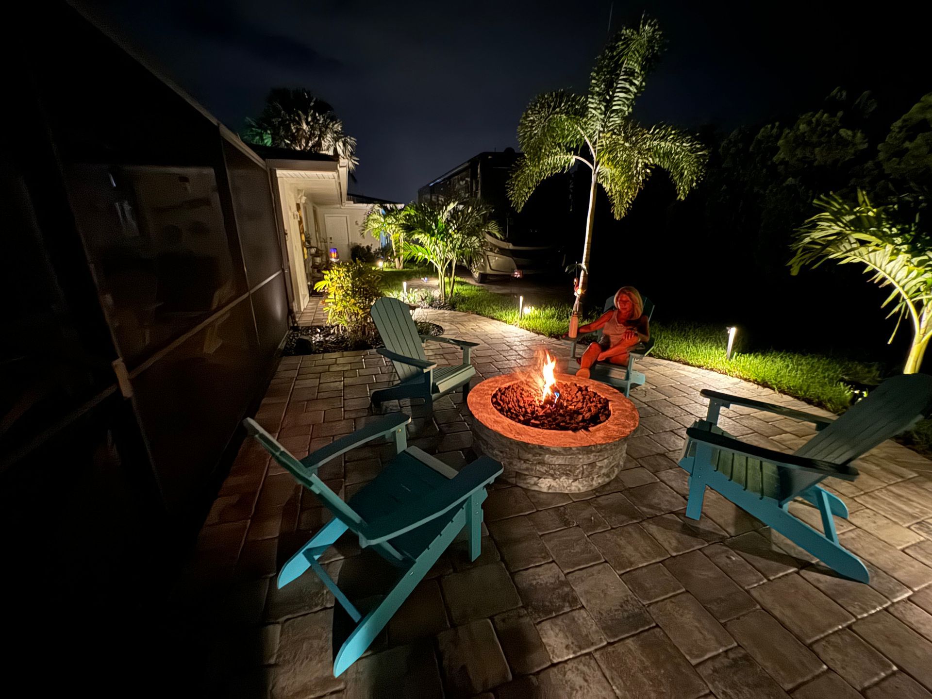 A fire pit surrounded by chairs on a patio at night.