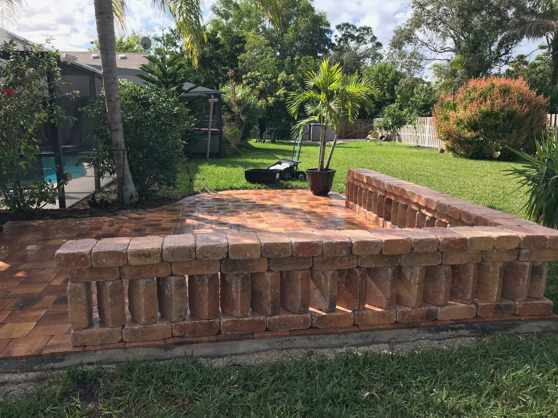 A brick wall in the backyard of a house next to a pool.