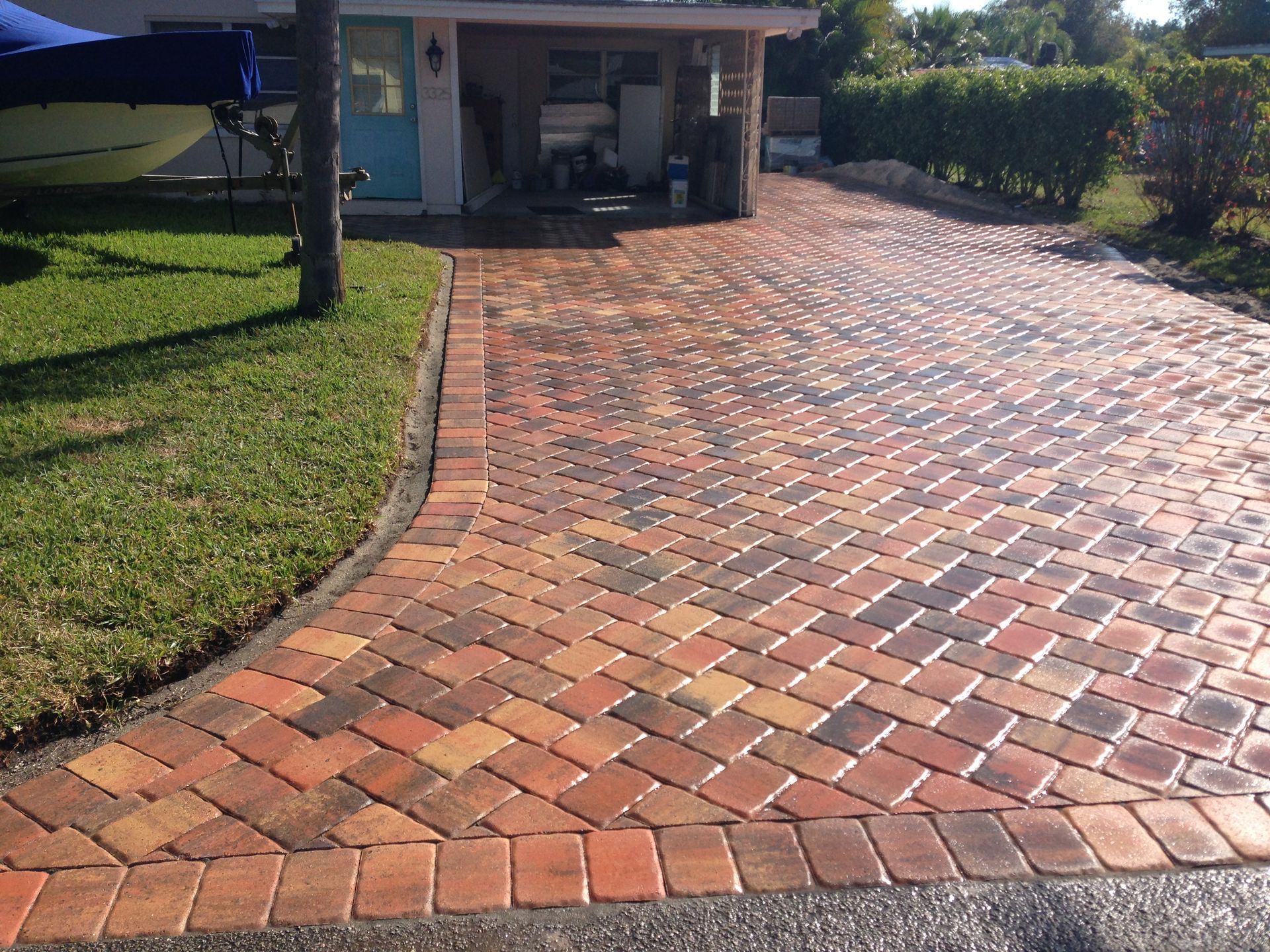 A brick driveway with a boat in the background