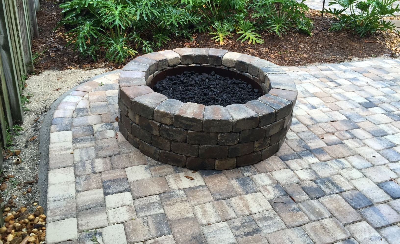 A fire pit is sitting on top of a brick patio.