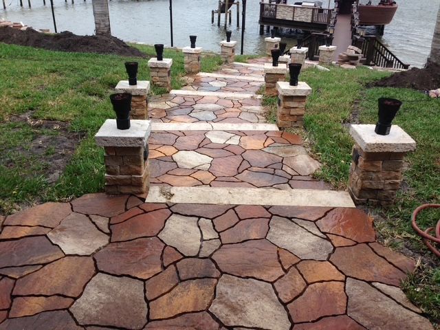 A stone walkway leading to a dock with a boat in the background