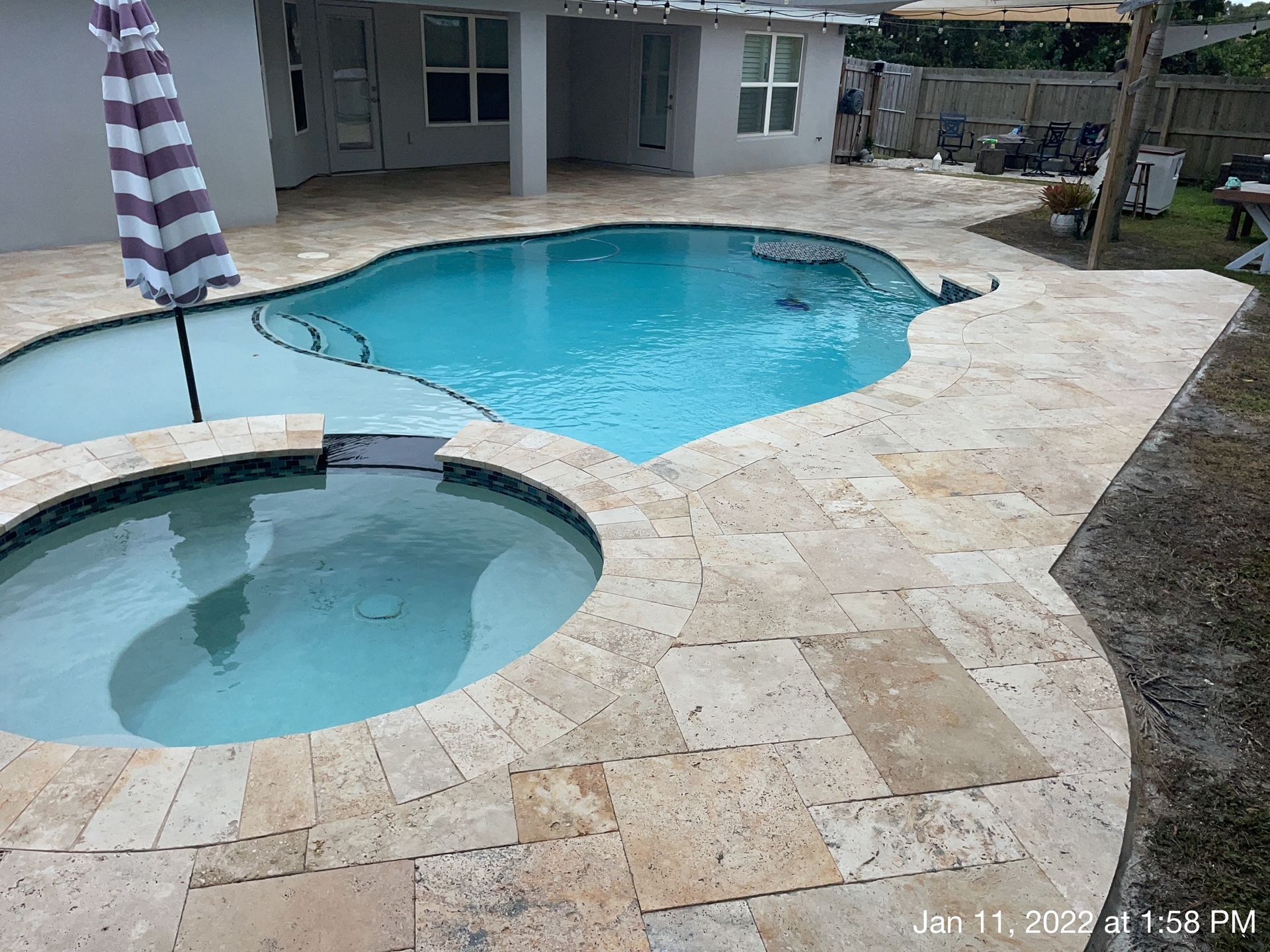 A large swimming pool with a hot tub next to it.
