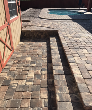 A brick walkway with stairs leading to a pool