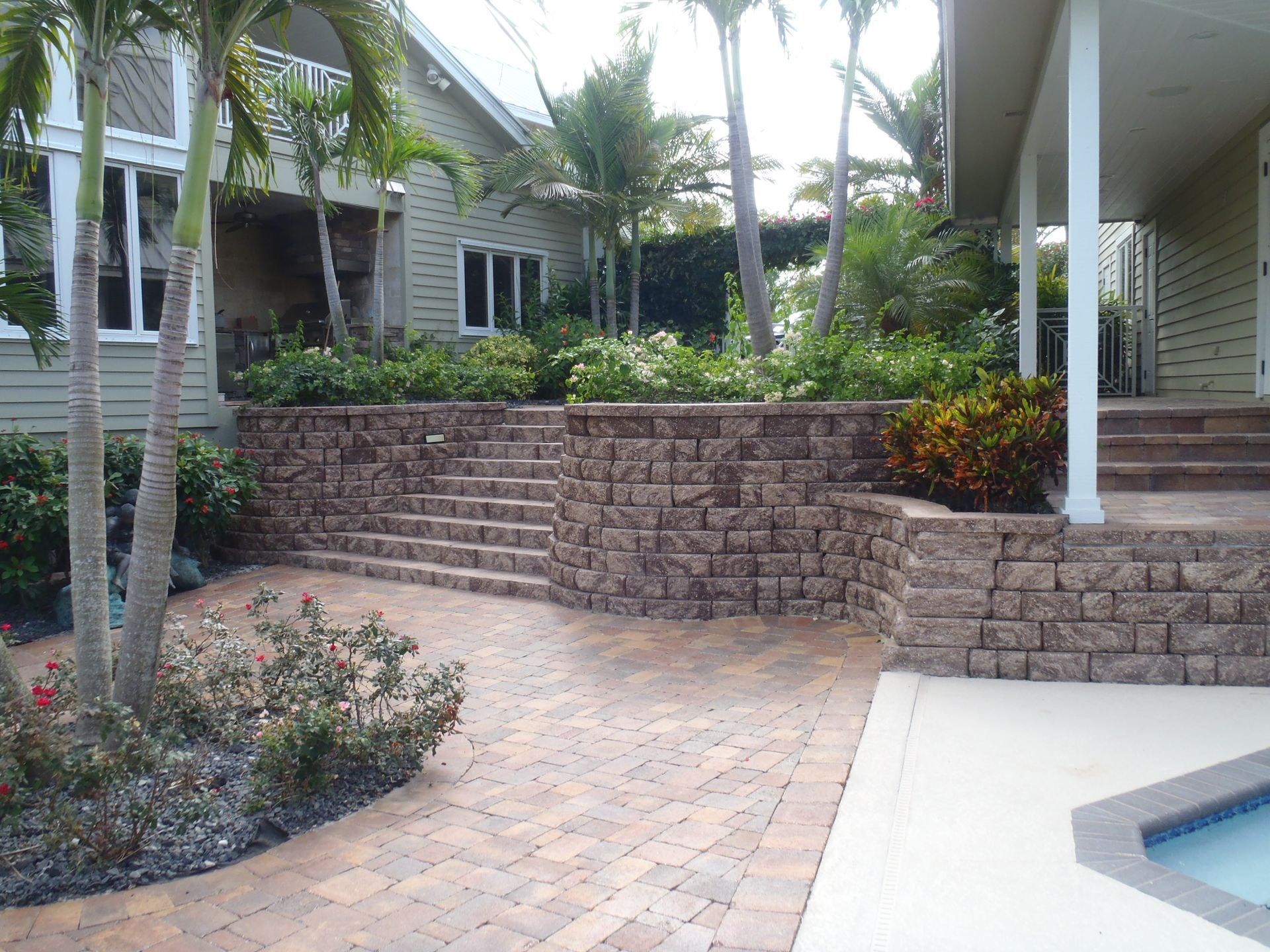 A brick walkway leading to a house with a pool