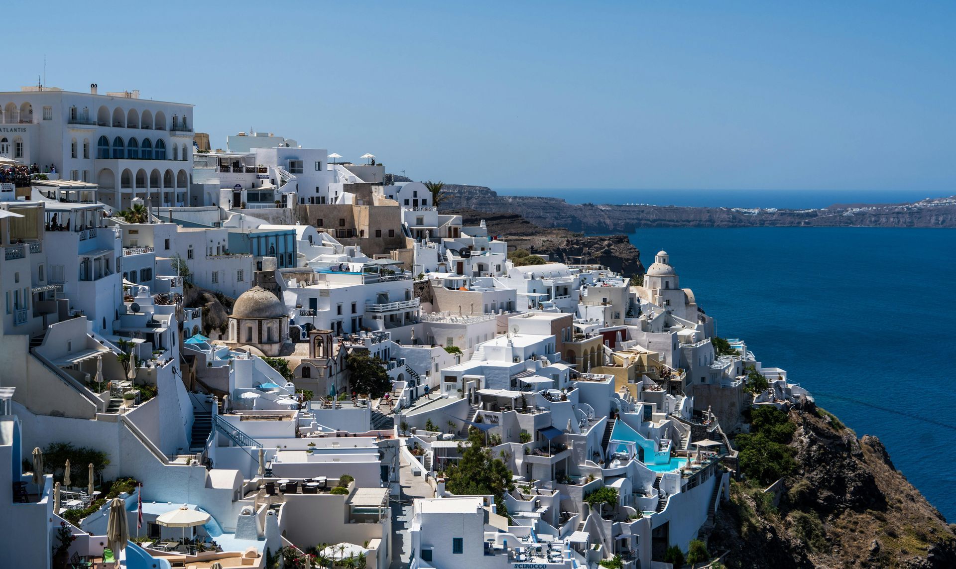 White cliffside buildings overlooking a deep blue sea under a clear sky.