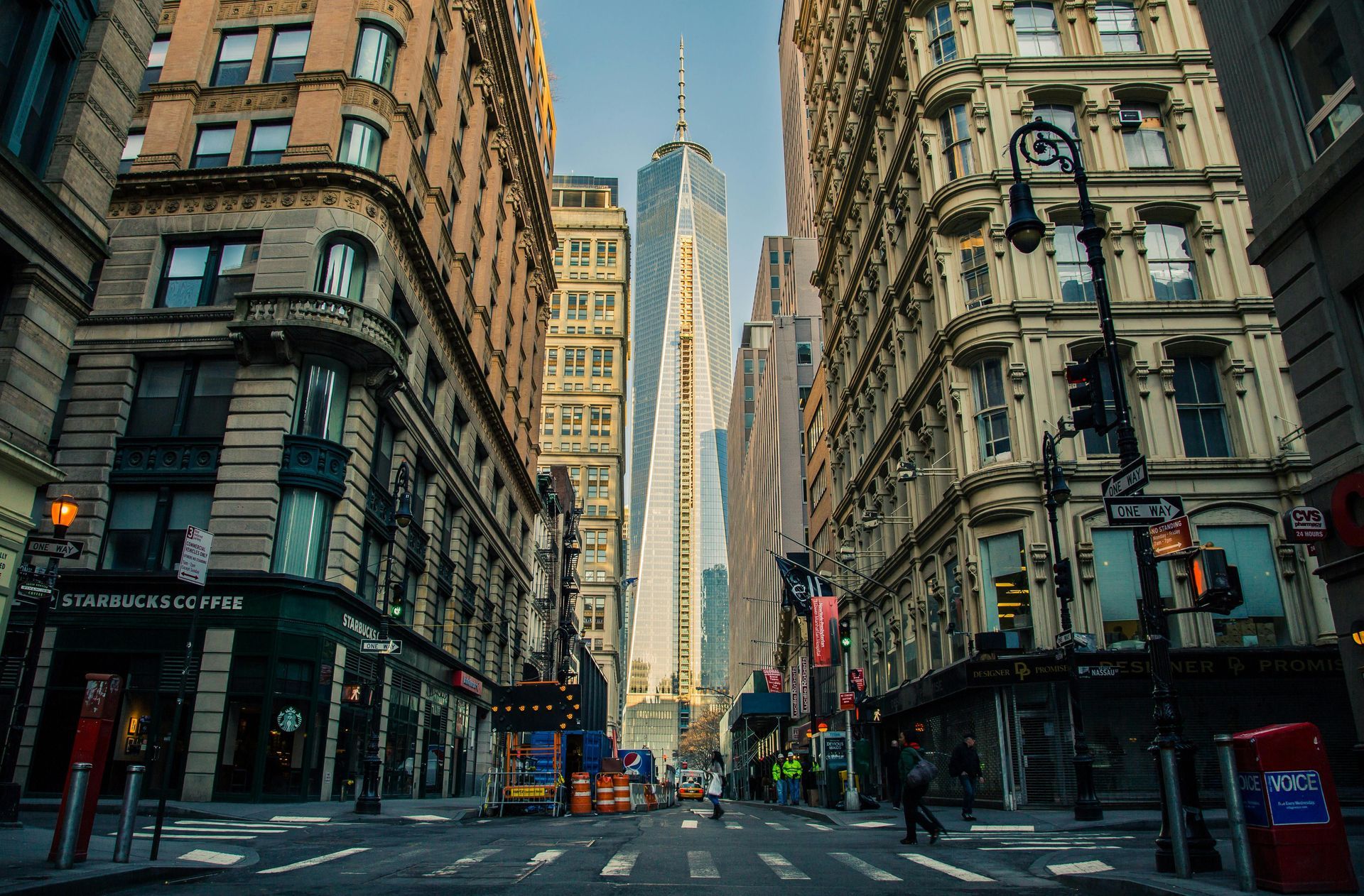 A city street framed by tall buildings, with the Empire State Building centered in the distance.