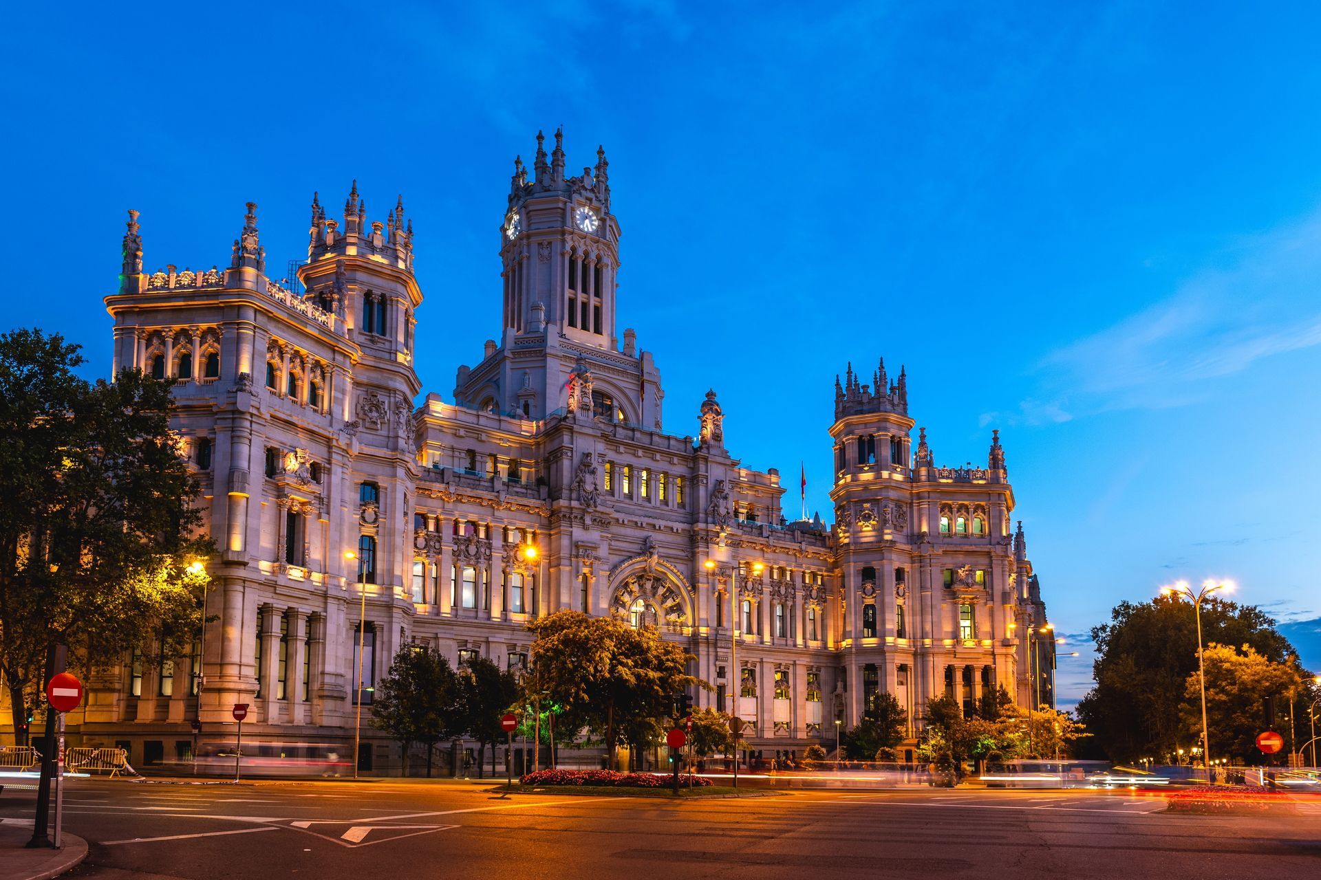 Illuminated historic palace at dusk with ornate towers and warm lights under a blue sky