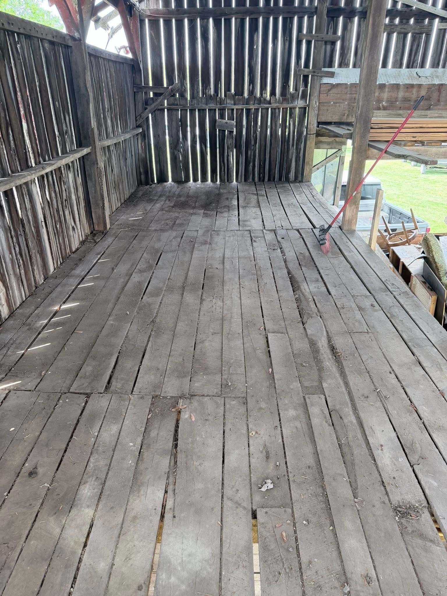 Weathered wooden deck beside a slatted fence, with a leaning board and scattered construction materials.