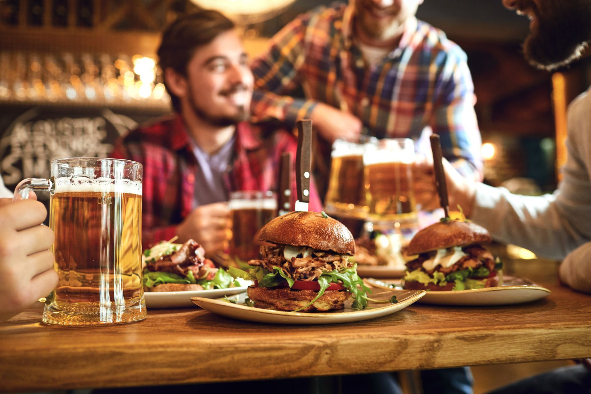 People at a bar with burgers and beer