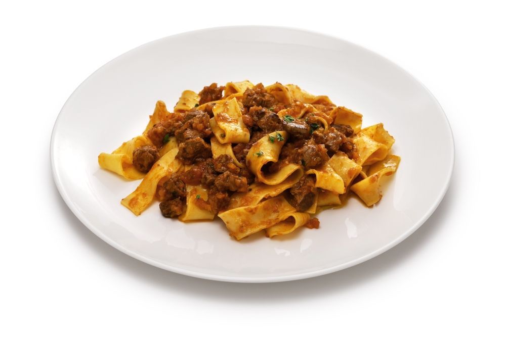 Pappardelle pasta with meat sauce served on a white plate.