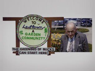 Levitown garden community sign with man standing beside it and the text “The greening of Bucks can start here”