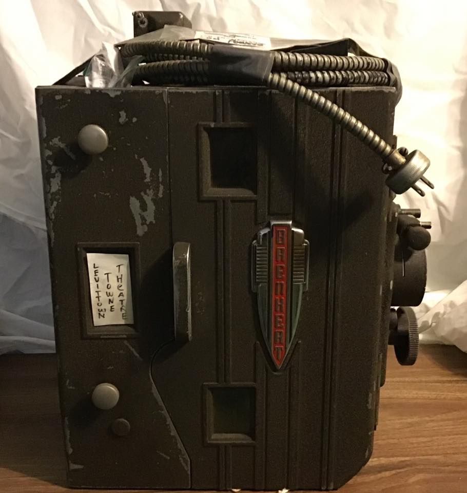 Black vintage box-like device with hose, vents, and knobs on a wooden surface