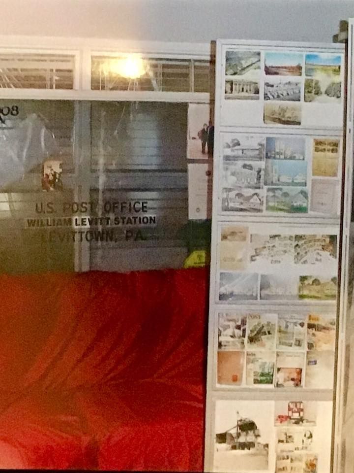 Indoor display with historical U.S. Post Office sign, red lower wall, and collage of vintage posters on the right.