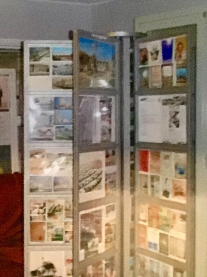 Three-panel display of brochures and photos in a room, with gray frames and warm lighting