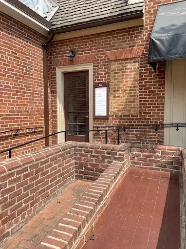 Brick building entrance with a ramp and handrails leading to a door