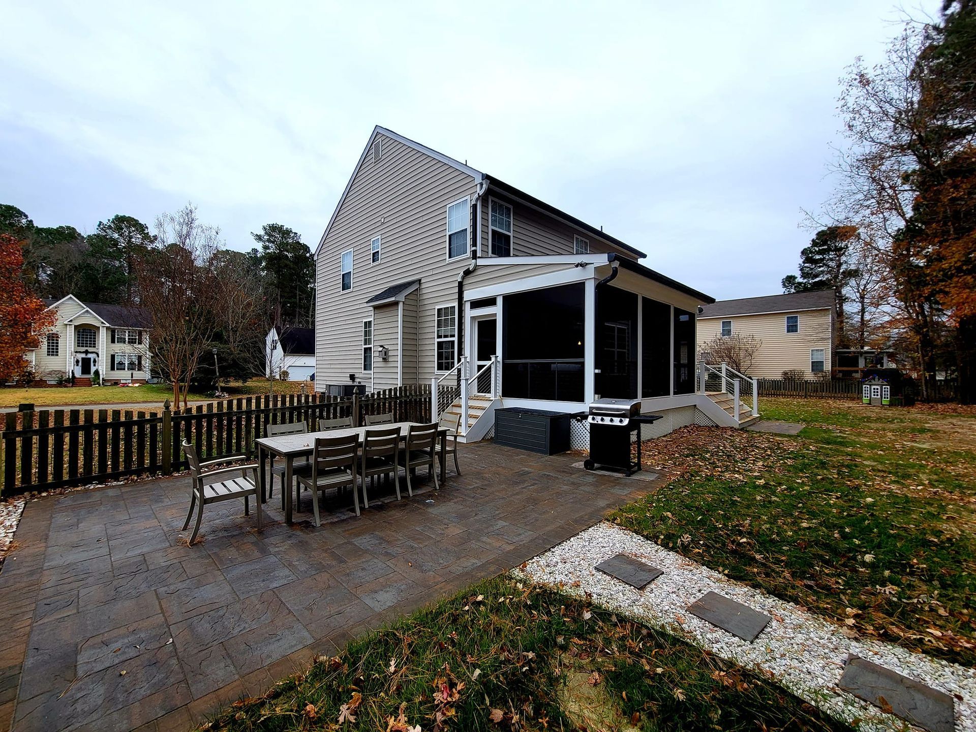 Outdoor patio with tables and chairs beside a white house on a cloudy day