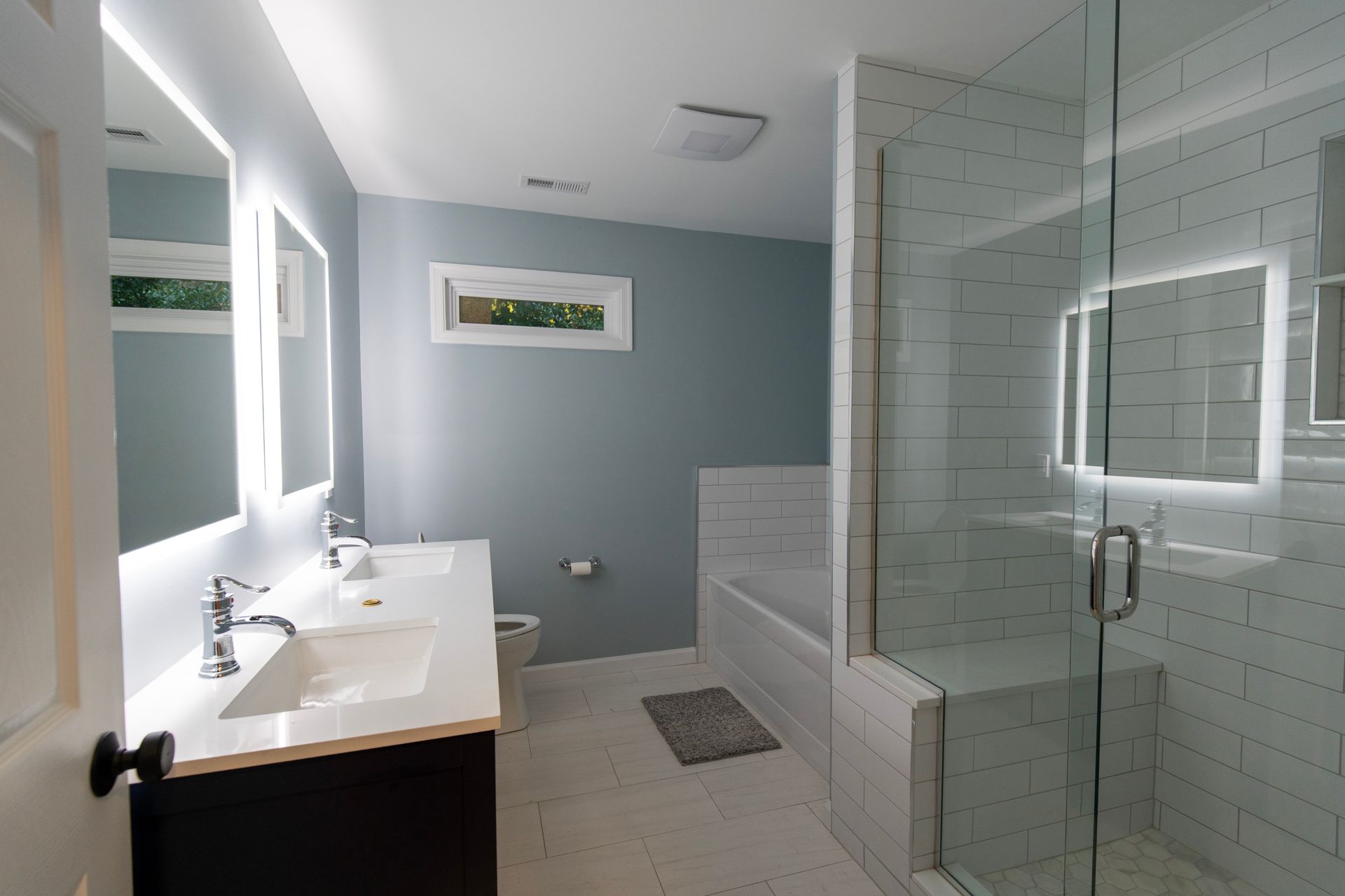 Modern bathroom with double sink vanity, glass shower, and white tile walls