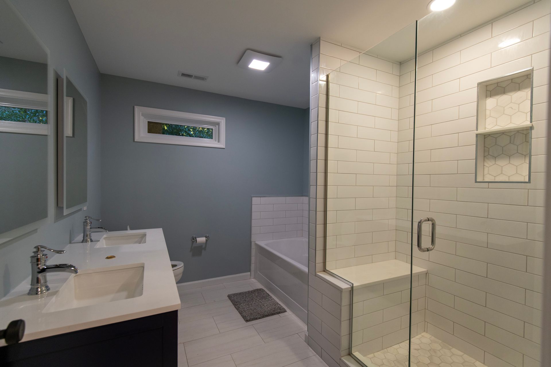 Modern bathroom with white vanity, tiled walk-in shower, and gray walls