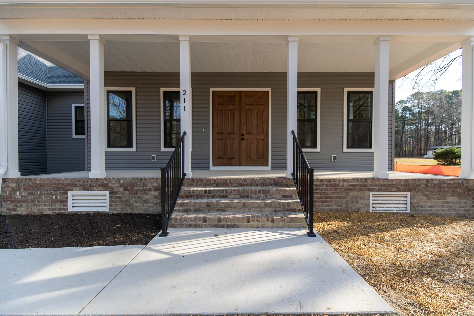 Front porch of a house with brick steps, white columns, and double wooden doors