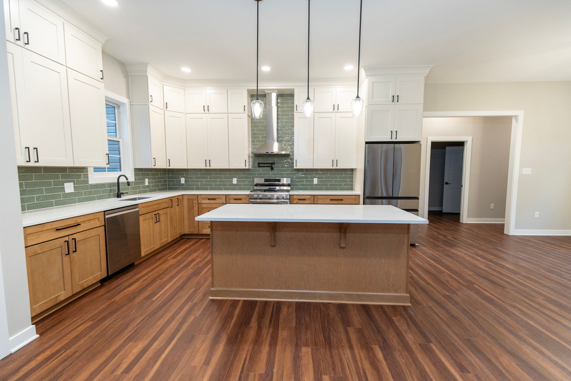 Modern kitchen with white cabinets, wood island, green tile backsplash, and hardwood floors