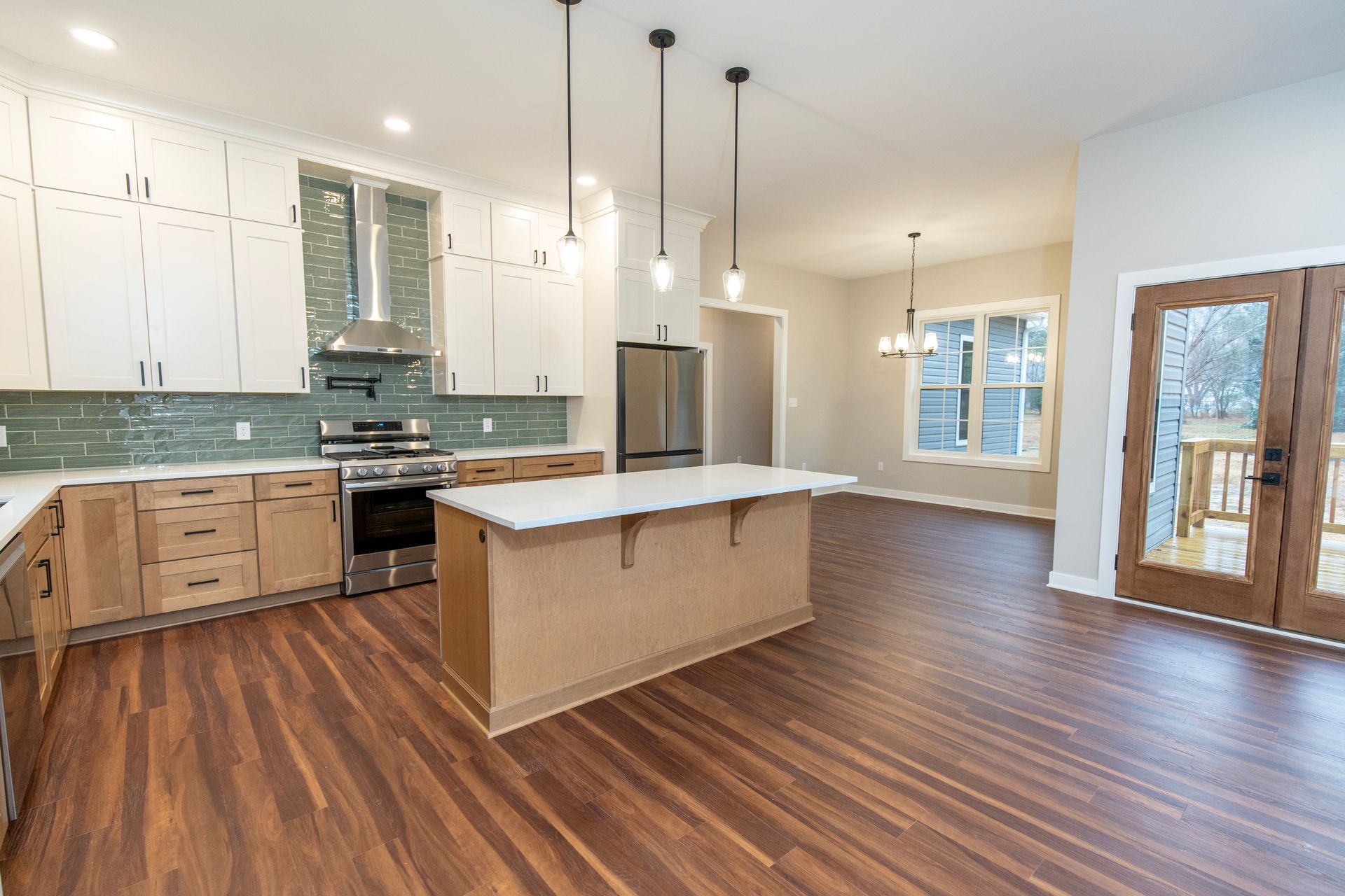 Bright modern kitchen with white cabinets, wood floors, island, and pendant lights