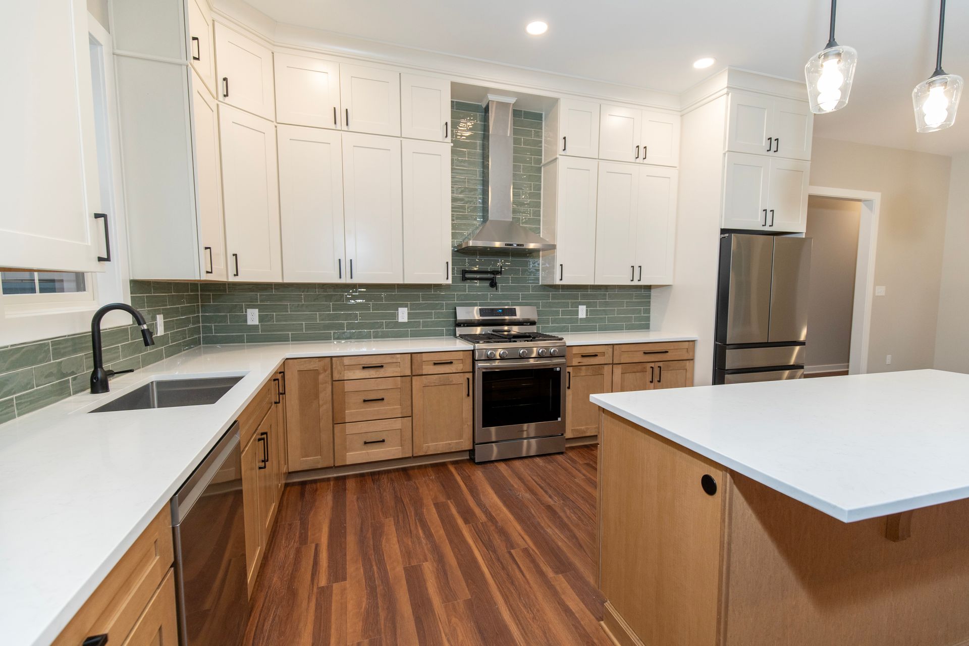 Bright modern kitchen with white cabinets, wood lower cabinets, stainless appliances, and a large island