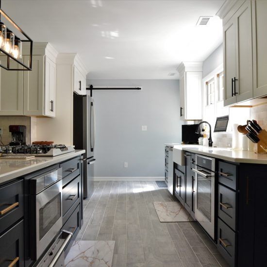 Modern galley kitchen with dark lower cabinets, light counters, and gray tile floor