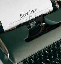 Typewriter with paper reading “Review” in a dark close-up view