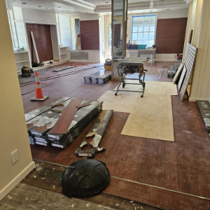 Renovated room with hardwood floors, stacked flooring materials, and tools under construction for repair work