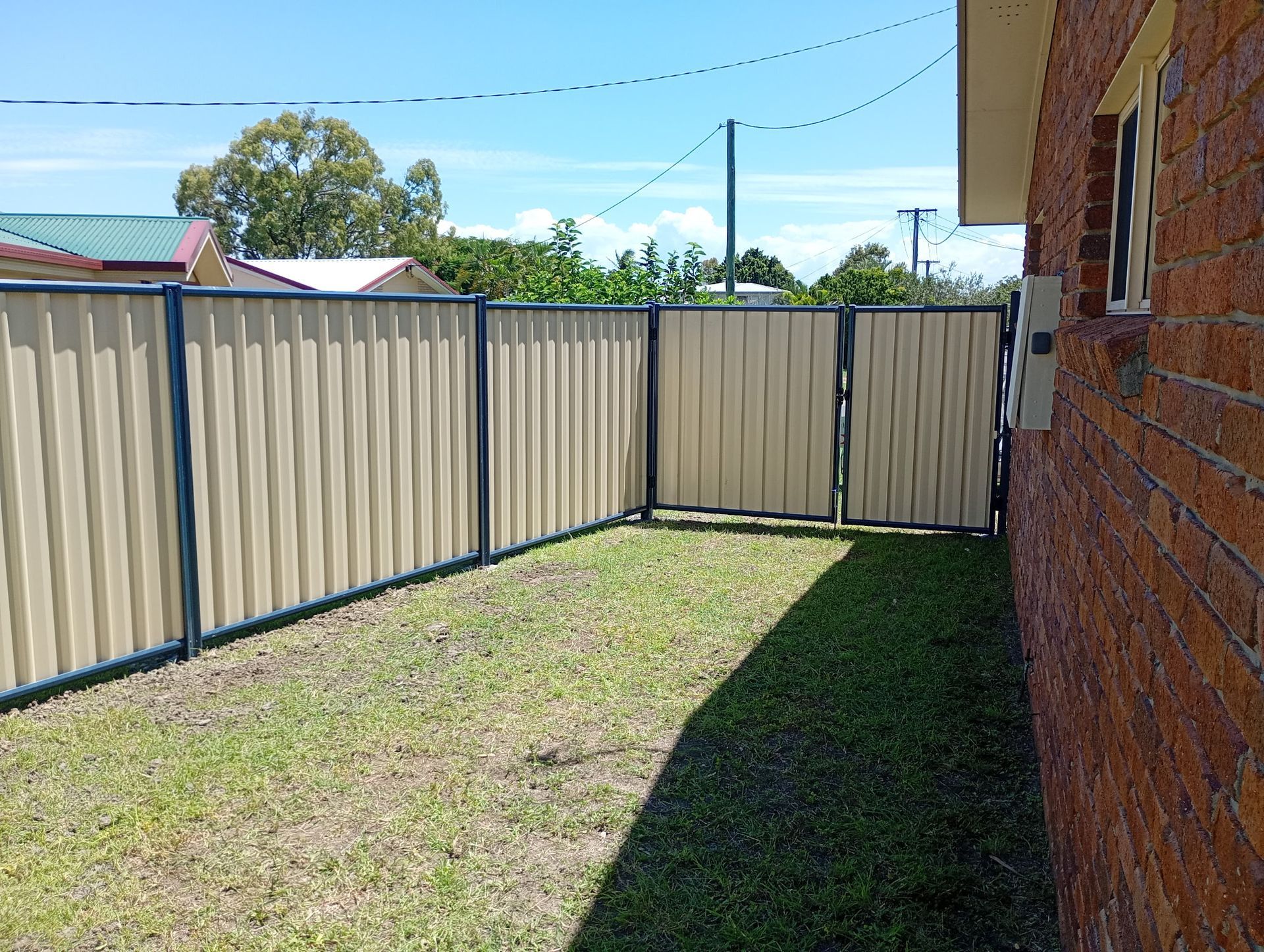 Tan and Brown Corrugated Metal Fence With a Slatted Design — The Fence Place in Kawana, QLD