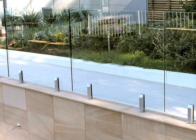 Glass Railing on a Stone Wall Overlooking a Garden and Sidewalk — The Fence Place in Port Kawana, QLD
