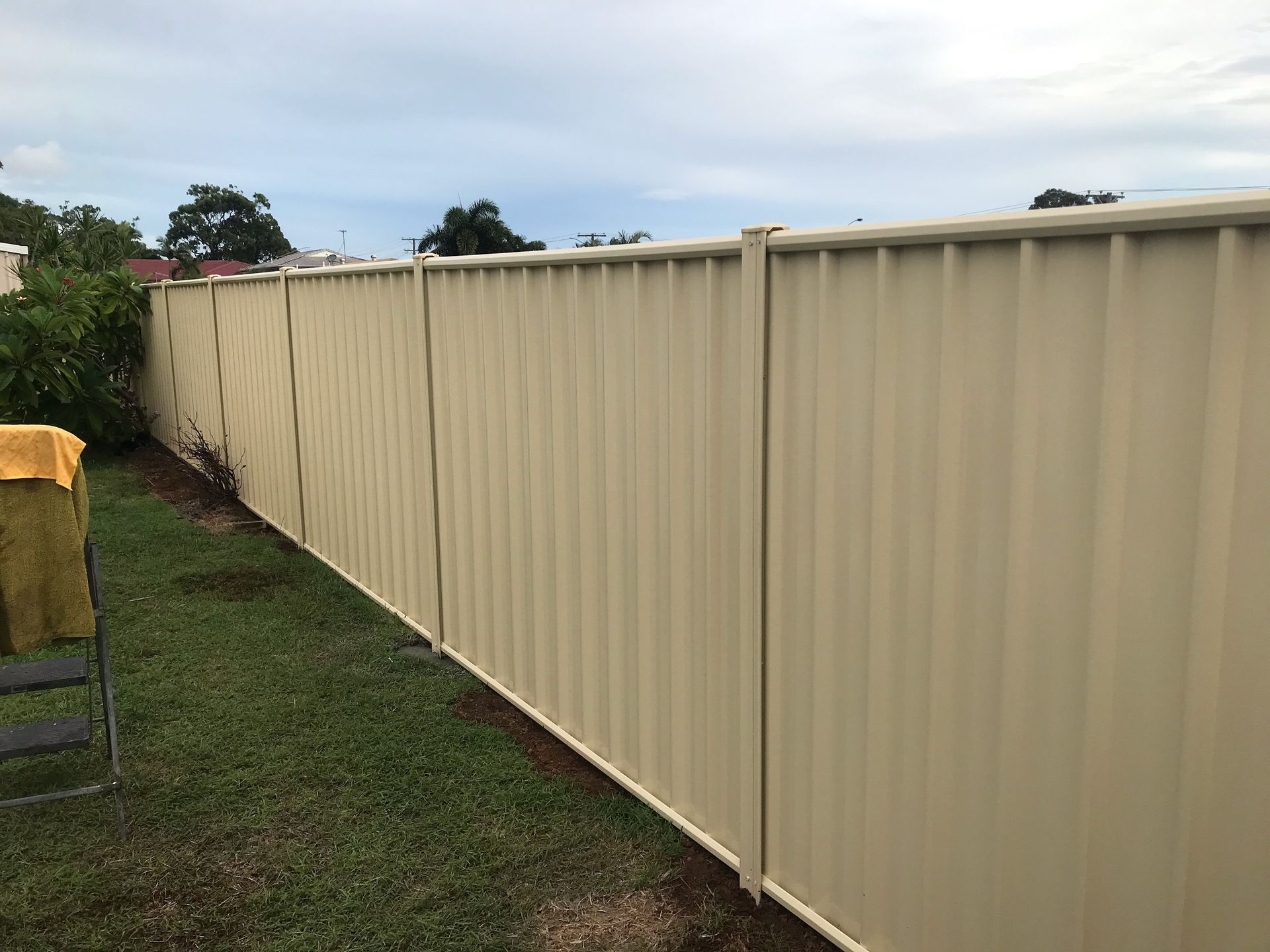Tan Vertical Corrugated Metal Fence in a Yard — The Fence Place in Kawana, QLD