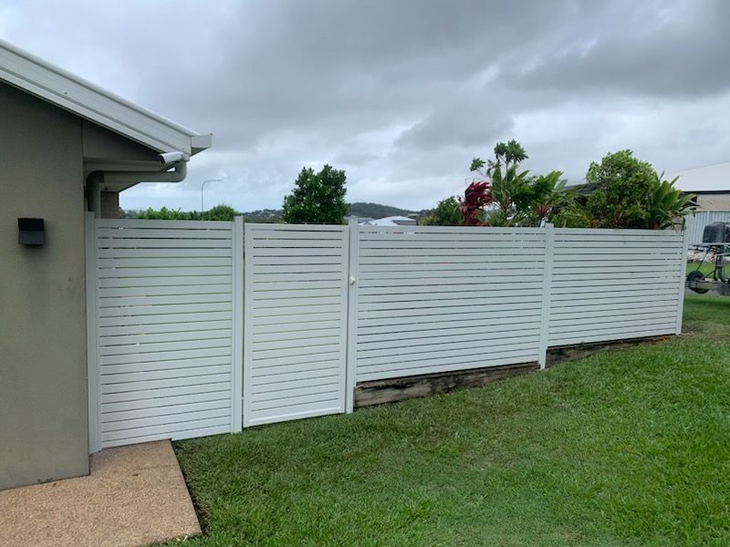 White Horizontal Slat Fence With Gate Next to a House and Green Lawn — The Fence Place in Kawana, QLD