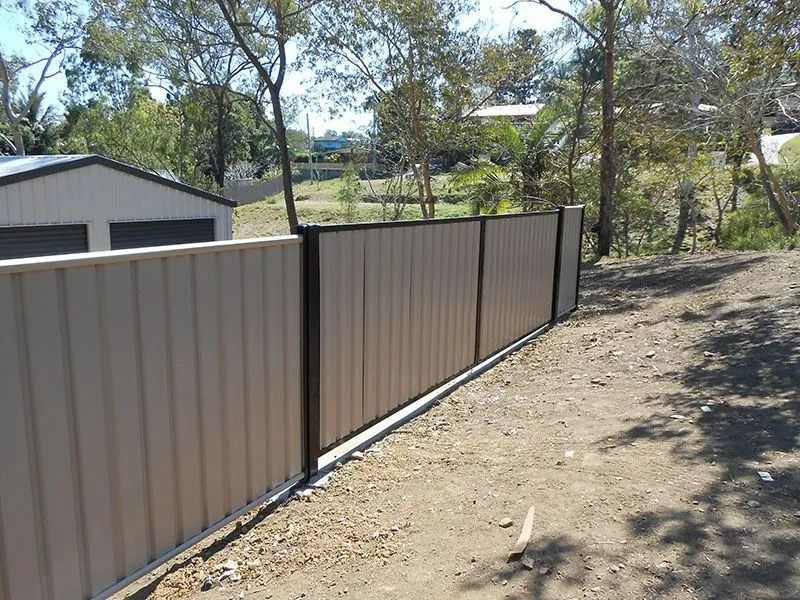 Beige Corrugated Metal Fence With Dark Brown Trim in a Yard — The Fence Place in Kawana, QLD