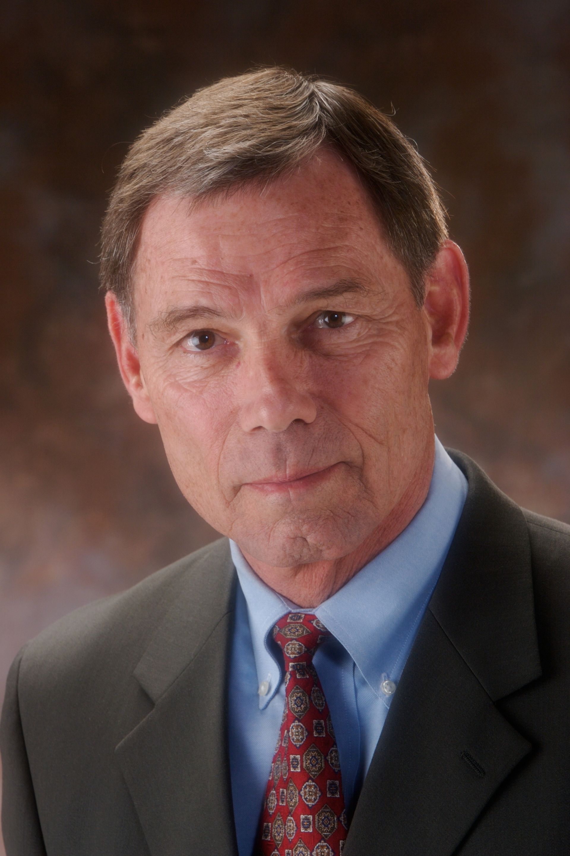 Man in suit and tie, looking at the camera, neutral expression.