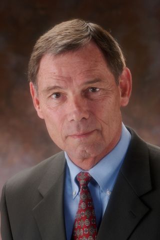 Man in suit and tie, looking at the camera, neutral expression.