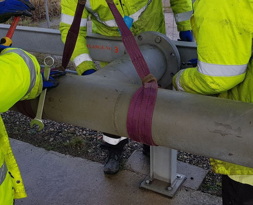 A man in a yellow jacket is working on a pipe