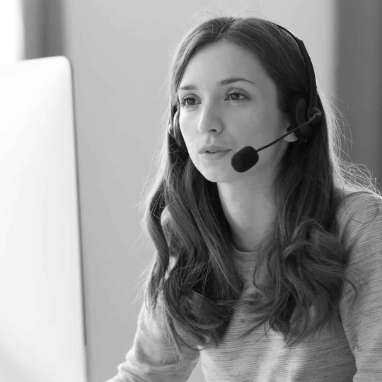 Woman wearing a headset working at a computer in a bright office