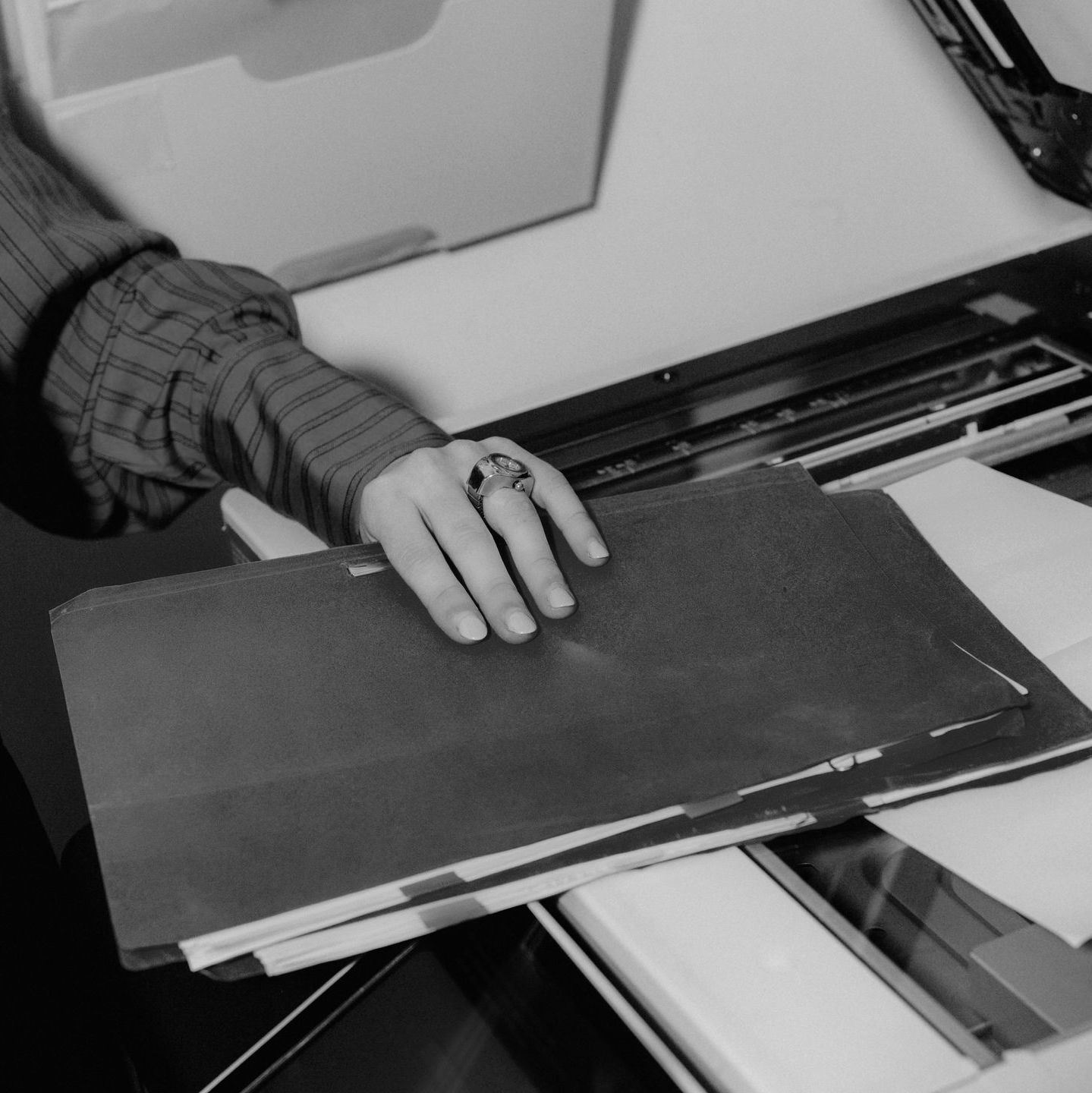 Hand sorting a stack of papers on a copier or printer tray