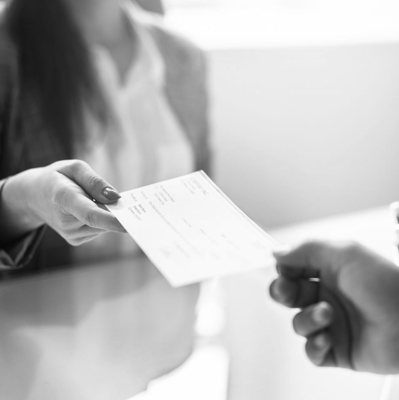 Handing over a check at a table, with a blurred person in the background