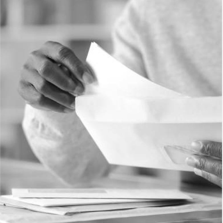Hands holding and folding a white sheet of paper over a stack of documents on a desk