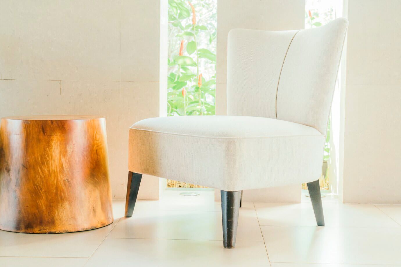 En una habitación luminosa y moderna, una silla tapizada en blanco con patas de madera