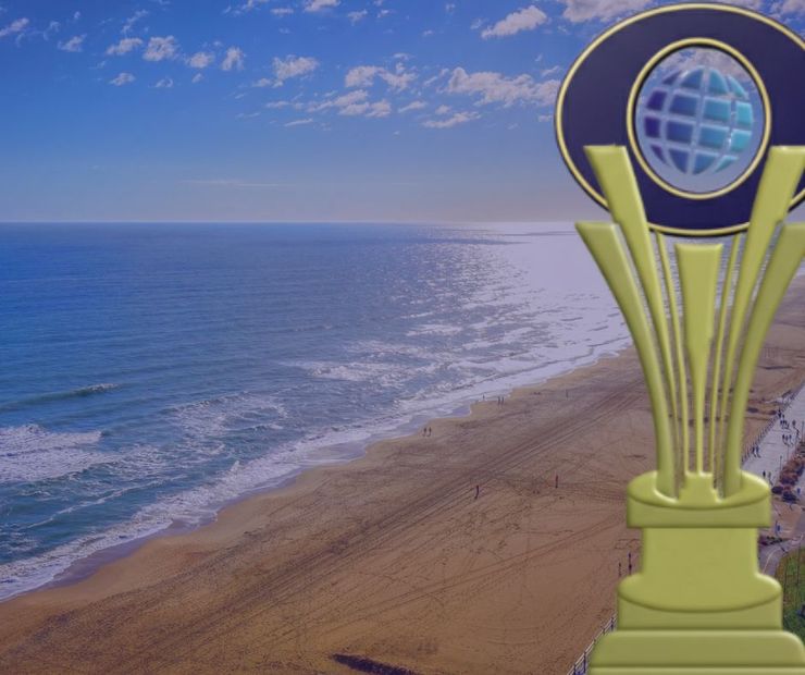 Gold trophy with globe over a beach and ocean view.