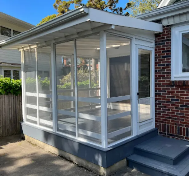 Screened-in porch attached to a brick house. White frame and screen walls, gray base, steps.