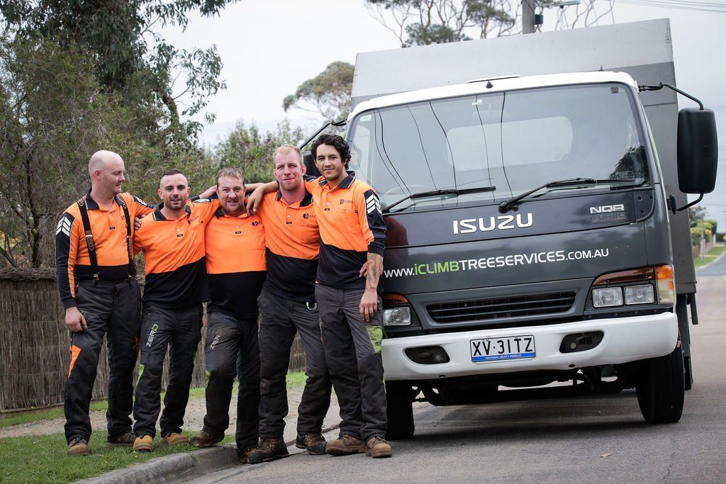 A group of men are posing for a picture in front of an isuzu truck.