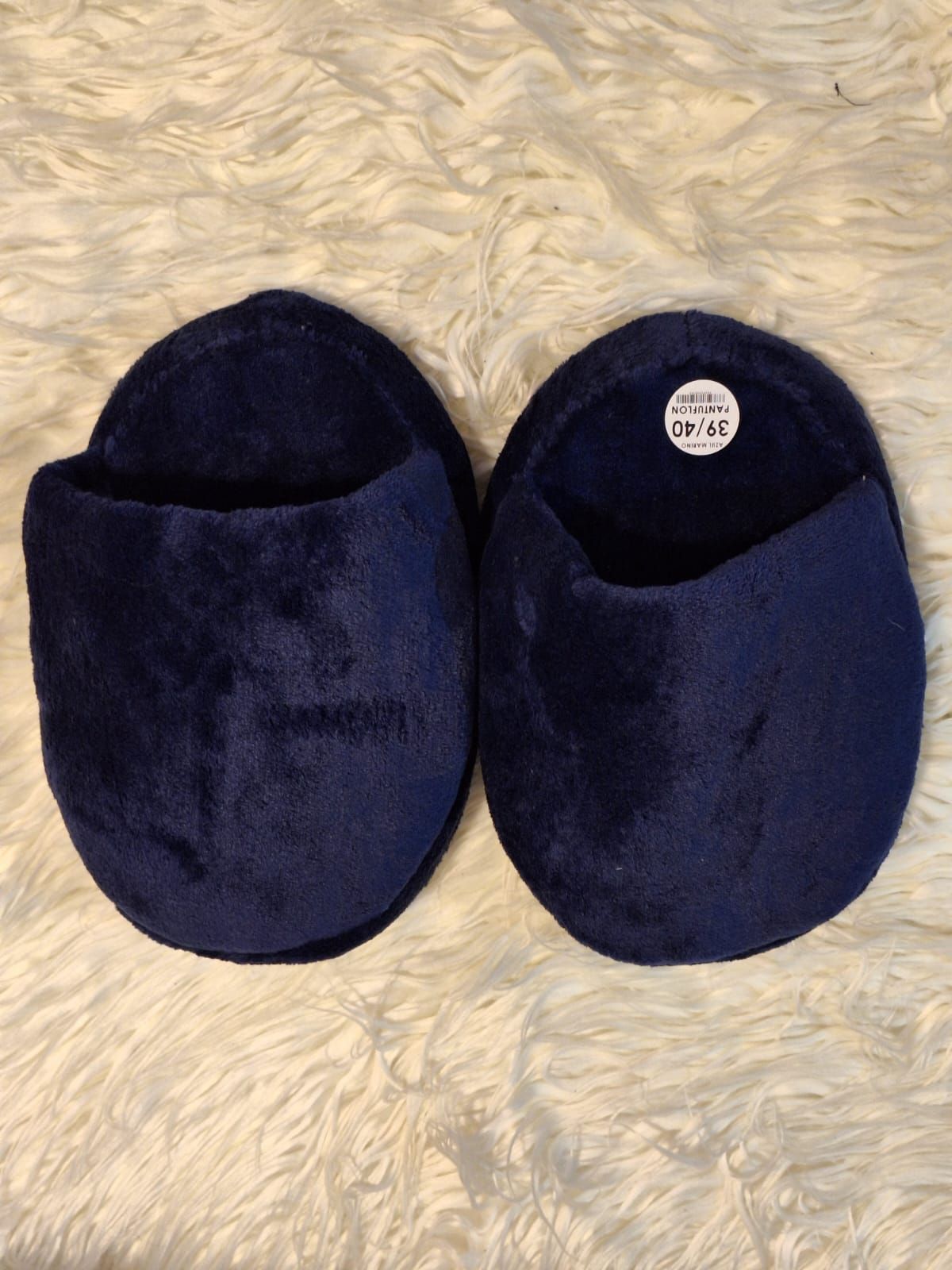Dos gorros de punto negros sobre una superficie de tela clara, uno de ellos doblado con la etiqueta visible.