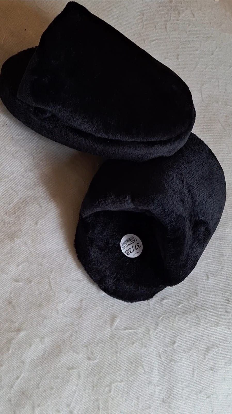 Dos gorros de punto negros sobre una superficie de tela clara, uno de ellos doblado con la etiqueta visible.